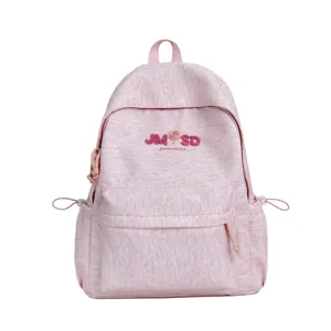 Detalle frontal de mochila escolar rosa jaspeado con letras bordadas y bolsillo delantero.