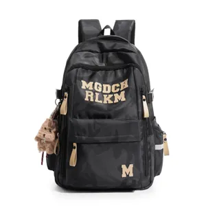 Detailed view of black camo student backpack with stylish letter patches and cute plush charm.