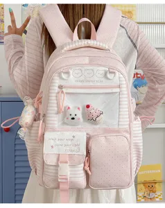 Dettaglio ravvicinato dello zaino da studente a pois rosa con tasca trasparente e simpatici peluche.