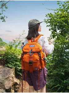 Detail des orangenen Outdoor-Rucksacks mit mehreren Taschen und langlebigen Schnallen.