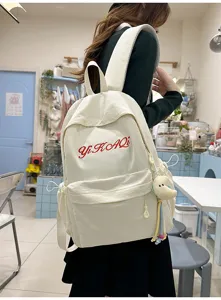 Nahaufnahme des minimalistischen weißen Studentenrucksacks mit roter Stickerei und Plüschmond.