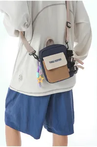 Gros plan détaillé du sac bandoulière colorblock montrant les sangles, boucles et poche avant.