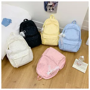 Vue détaillée de sacs à dos mignons avec motif cœur en plusieurs couleurs sur sol en bois.