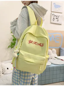 Modischer minimalistischer hellgelber Schulrucksack mit roter Buchstabenstickerei für Schüler.