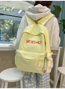 Detailansicht des hellgelben Rucksacks mit roter Stickerei und niedlichem Anhänger.