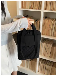 Vista di dettaglio di una borsa tote trapuntata in nylon nero con tasca frontale elegante.