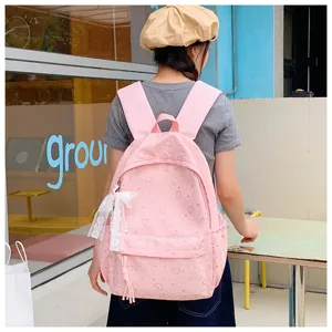 Vue détaillée du joli sac à dos rose avec motif de cœurs et charmant pendentif en dentelle.