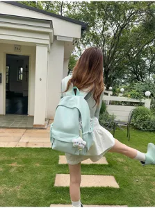 Dettaglio zaino da scuola in nylon verde chiaro, zainetto casual giornaliero con ciondolo.