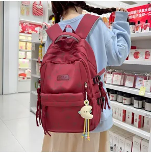 Red star print canvas school backpack detail view with cute moon pendant and multiple pockets