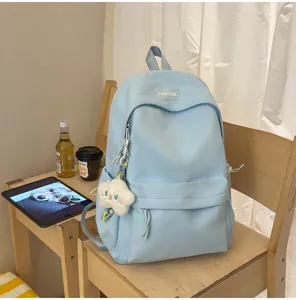 Dettaglio zaino in nylon azzurro, borsa scolastica casual quotidiana con grazioso ciondolo.
