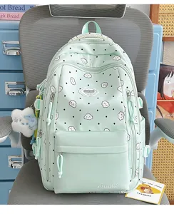 Detailansicht des niedlichen hellgrünen Rucksacks mit Wolkenprint, Anhänger und vielen Taschen.