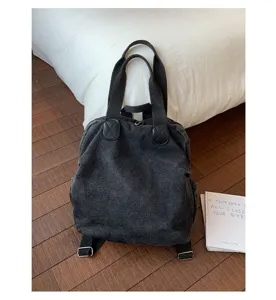 Vue détaillée du sac à dos convertible en denim lavé gris foncé avec poignées solides.