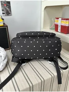 Vista dettagliata del simpatico zaino nero a pois bianchi, con spallacci visibili.