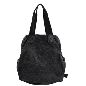 Vue rapprochée du sac à dos en denim noir lavé, mettant en valeur la texture résistante.