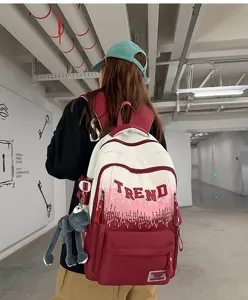 Gradient backpack detail showing large red lettering, roomy compartments, and cute doll pendant.