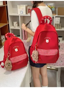 Roter Schulrucksack mit Karotasche, Bärenaufnäher und Plüschhundanhänger für Schüler.