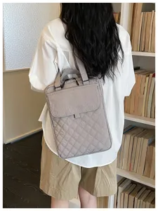 Vista dettagliata dello zaino tote in nylon trapuntato grigio con tessuto strutturato e manici.