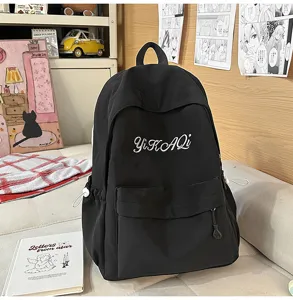 Detailansicht des schwarzen Canvas-Schulrucksacks mit eleganter weißer Buchstabenstickerei.