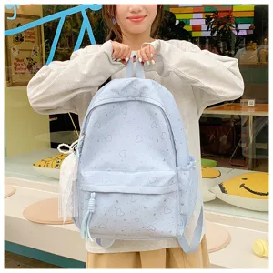 Vue détaillée du joli sac à dos bleu clair imprimé cœurs avec pendentif et poches décor.
