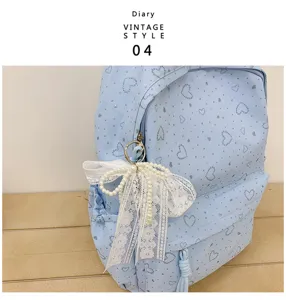 Détail du sac à dos bleu clair avec motif de cœur et charmant nœud en perles et dentelle.