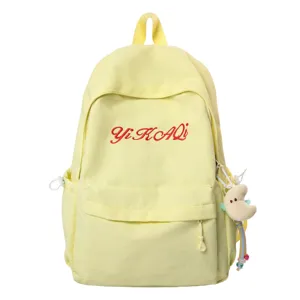 Leichter gelber Schulrucksack fuer Maedchen mit roten gestickten Buchstaben und suessem Anhaenger.
