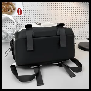 Vue détaillée d'un grand sac à dos noir pour étudiant, avec sangles et boucles robustes.