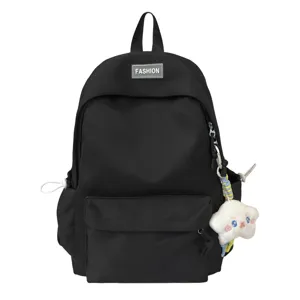 Dettaglio zaino scolastico in nylon nero con tasca frontale e grazioso ciondolo in peluche.