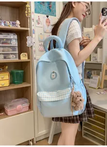 Niedlicher hellblauer Studentenrucksack mit Karotasche und flauschigem Anhänger für die Schule.
