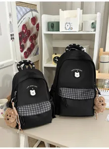 Niedlicher schwarzer Schulrucksack mit Karotasche, Bären-Patch und Plüschhund-Anhänger.