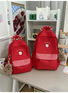 Niedlicher roter Schulrucksack mit Karomantel, Bärenaufnäher und Plüschanhänger für Schüler.
