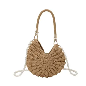 Détail du sac coquillage en crochet beige avec tissage fin et élégante bandoulière perle.