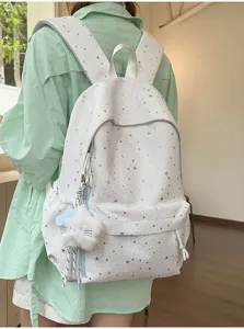 Detailansicht des weißen Rucksacks mit Sternenmuster und süßem flauschigen Plüschanhänger.