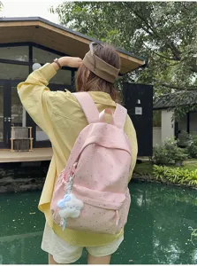 Rosa Segeltuch Schulrucksack mit silbernen Sternen und süßem Plüschanhänger für Schüler.