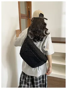 Schwarze Nylon Umhängetasche am Model getragen, zeigt grosses Volumen und ideal für den Alltag.