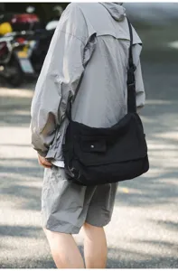Schwarze Canvas-Umhängetasche Detailaufnahme mit Schultergurt und Fronttaschen-Klappendesign.