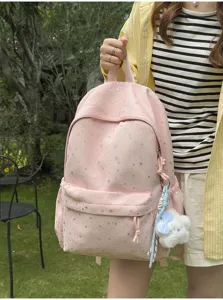Nahaufnahme eines süßen rosa Rucksacks mit Sternenmuster und Plüschtier-Anhänger.