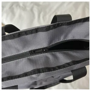 Dettaglio borsa shopper in tela grigia, grande capacità borsa casual da lavoro con chiusura lampo.