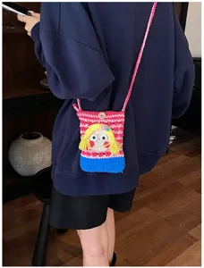 Nahaufnahme einer niedlichen handgemachten Häkel-Handy-Umhängetasche mit Cartoon-Mädchen-Design.