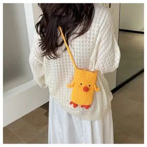 Detail shot of a cute handmade knitted cartoon duck phone bag worn crossbody style indoors.