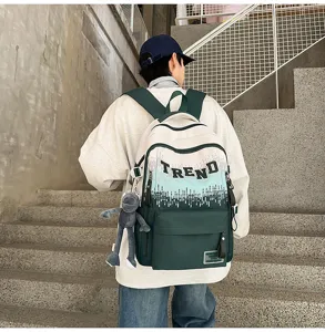 Detail view of large capacity canvas backpack with gradient trendy letter print and doll charm.