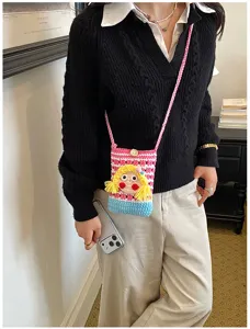 Detailansicht der süßen gestrickten Handytasche mit Cartoon-Puppengesicht und bunten Farbblöcken.