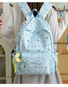 Cute light blue star print student backpack detail view with multiple pockets and moon pendant.