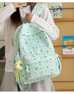 Detailed close-up view of mint green star print school backpack with cute plush pendant.