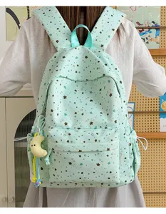 Close-up detail of the mint green star print student backpack with side pockets and cute charm.