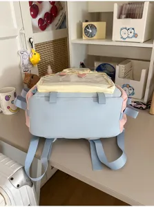 Primo piano di uno zaino Ita pastello blu e rosa con finestra trasparente per spille e gadget.