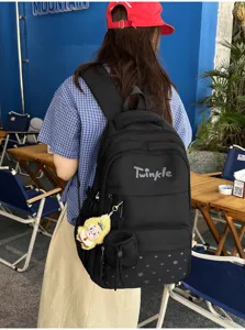 Detailed view of black student backpack with star print, large capacity and cute pendant.