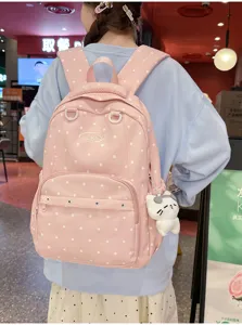 Vue détaillée d'un sac à dos rose à pois avec un pendentif chat mignon porté en scène.