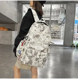 Detailed shot of the multi-compartment fashion camouflage backpack with bear pendant.