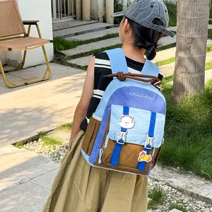 Detail view of color-blocking children backpack featuring multi-pockets and cute cartoon patches.