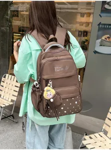 Stylish brown star print backpack with multiple compartments and cute plush charm detail.
